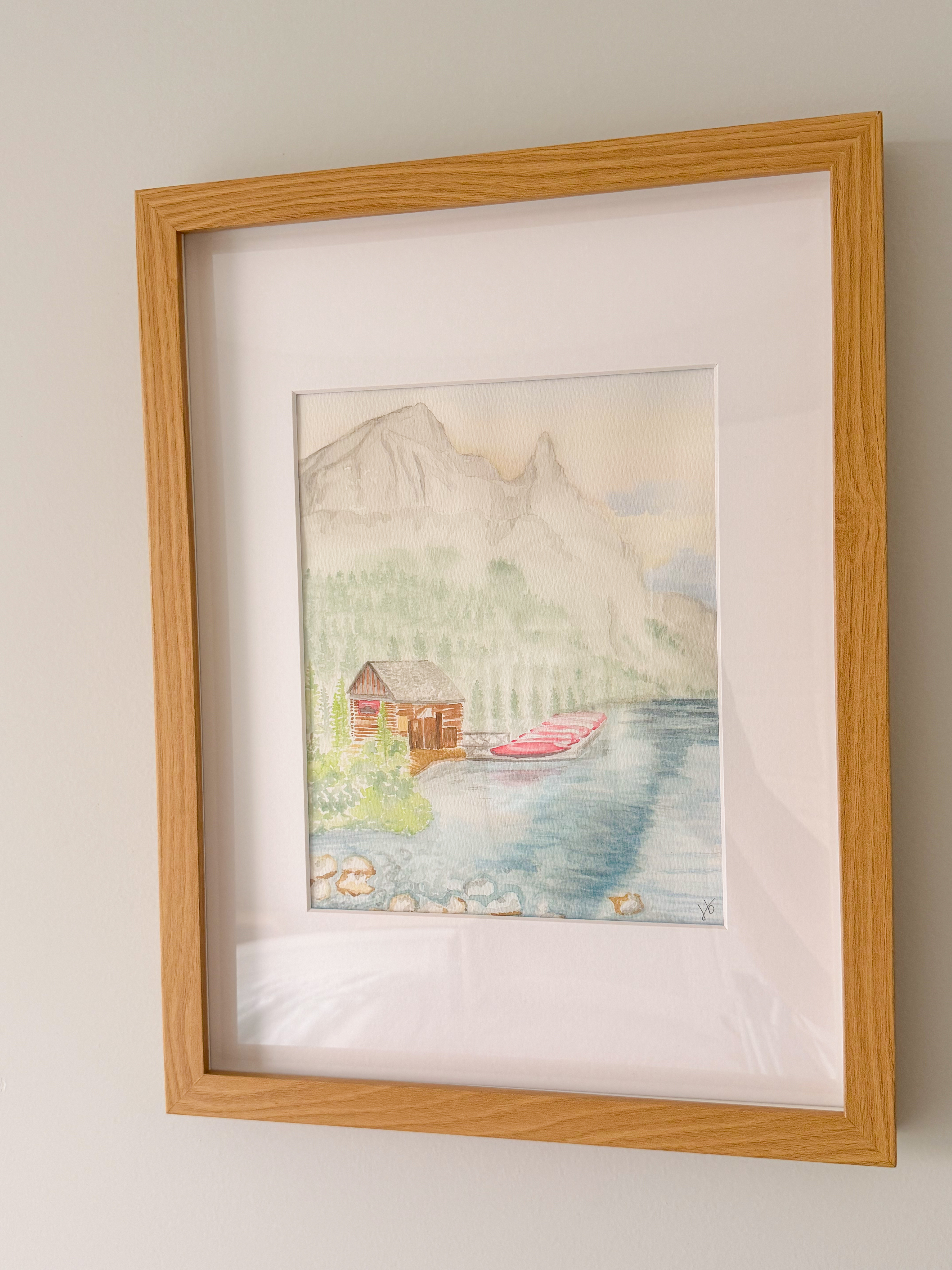 Framed watercolor of a small cabin besides Lake Louise