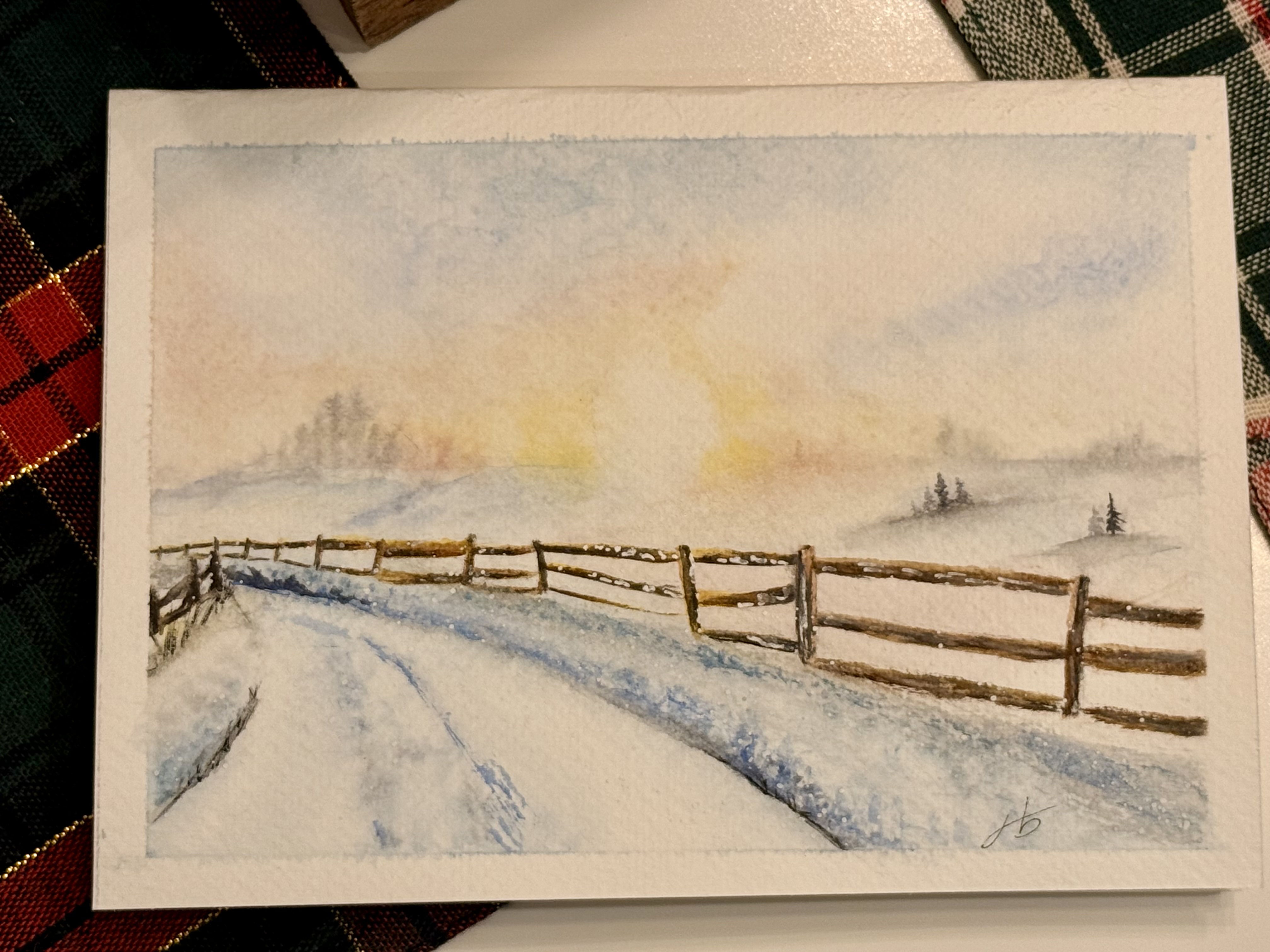 Loose watercolor of a snowy field at sunrise with a wooden fence in the foreground
